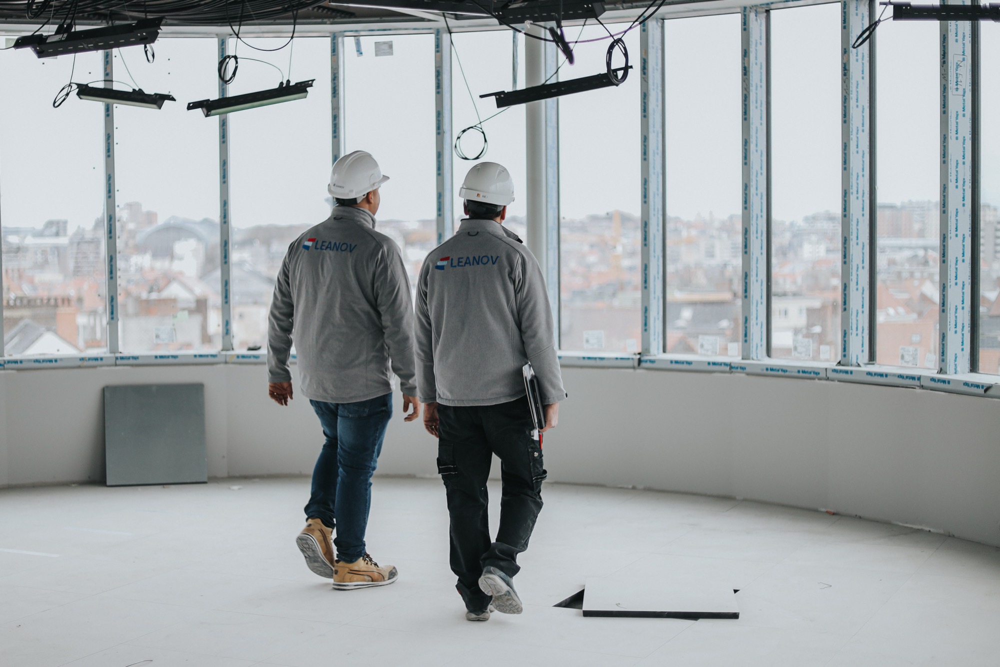 Técnicos LEANOV a percorrer piso amplo em obra com vista urbana