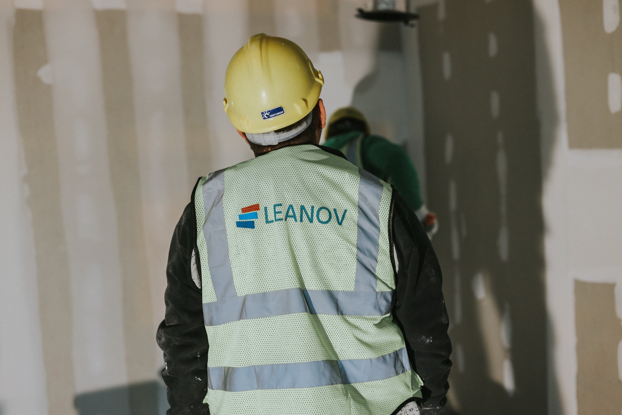 Colete com a marca LEANOV num operário em obra visto de costas