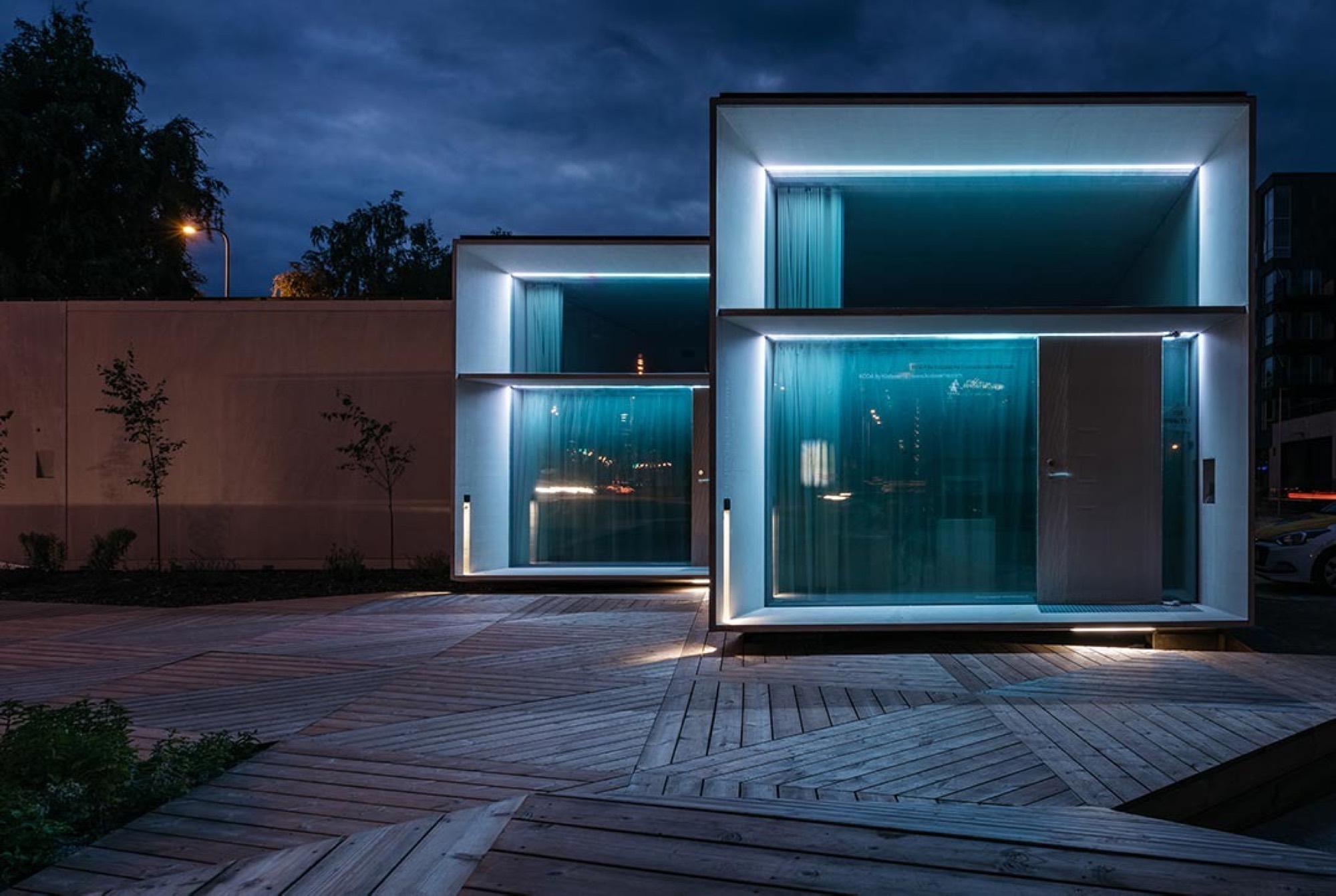 Casa modular LEANOV iluminada ao anoitecer sobre deck de madeira